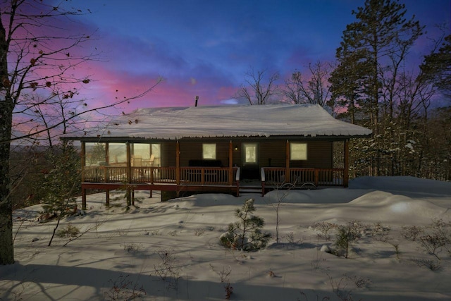 snow covered rear of property featuring a porch