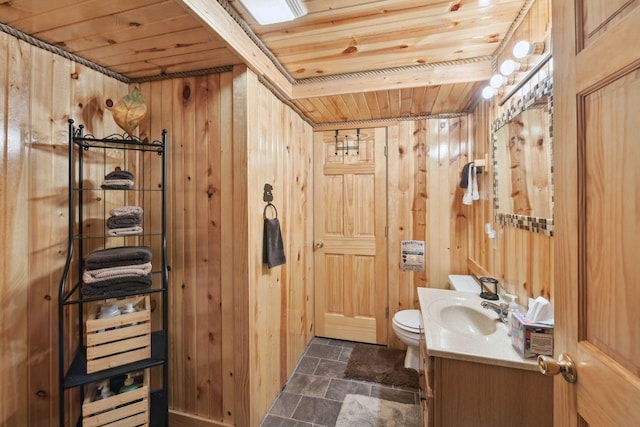 bathroom with wood ceiling, wooden walls, vanity, and toilet