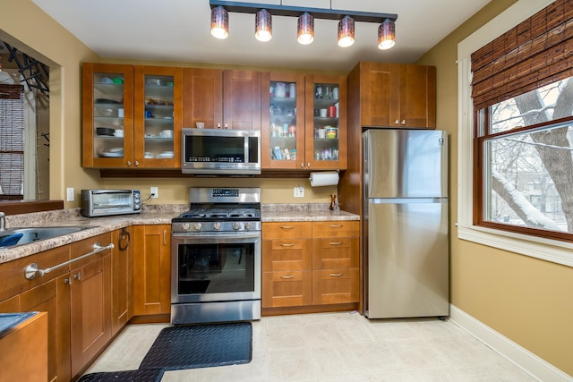 kitchen featuring stainless steel appliances, glass insert cabinets, and brown cabinets