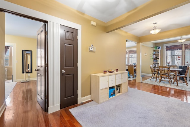 interior space featuring dark wood-type flooring, beamed ceiling, and baseboards