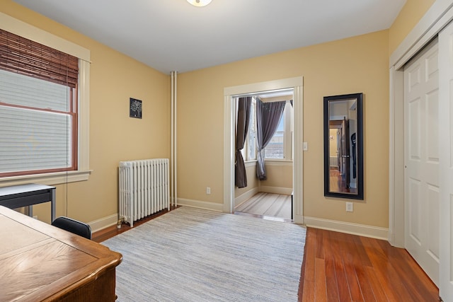 bedroom with radiator heating unit, dark wood finished floors, and baseboards