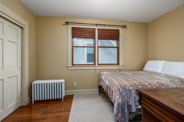 bedroom featuring radiator, dark wood-style floors, and baseboards