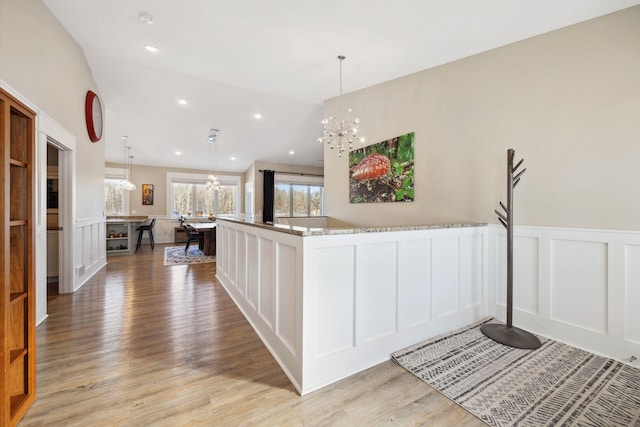 kitchen with lofted ceiling, pendant lighting, white cabinets, and light stone counters