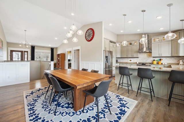 dining room featuring a notable chandelier, light hardwood / wood-style floors, and high vaulted ceiling