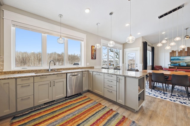 kitchen with sink, dishwasher, light stone countertops, decorative light fixtures, and light wood-type flooring