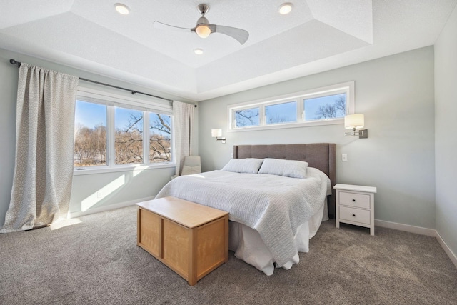 carpeted bedroom with a tray ceiling and ceiling fan