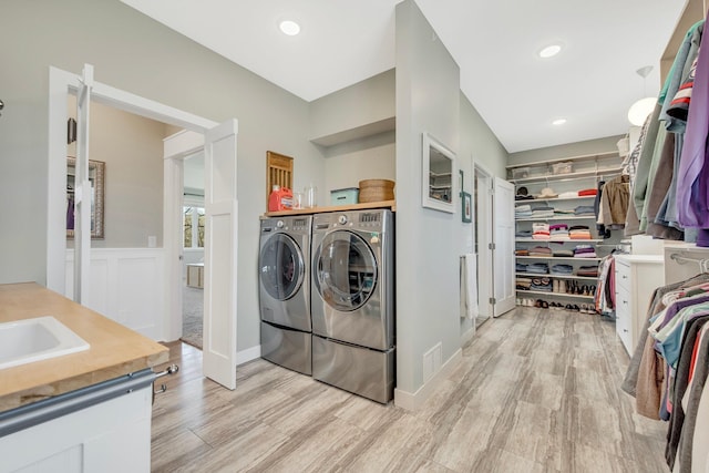 laundry room featuring separate washer and dryer, sink, and light hardwood / wood-style floors