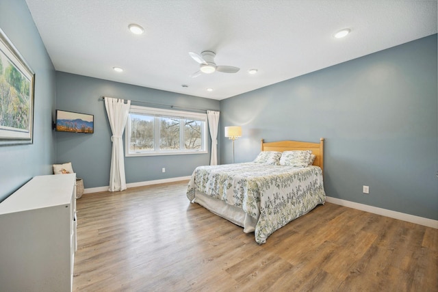 bedroom featuring ceiling fan, hardwood / wood-style floors, and a textured ceiling