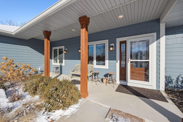 snow covered property entrance with a porch