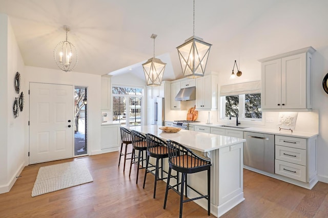 kitchen with a notable chandelier, a kitchen island, pendant lighting, stainless steel appliances, and white cabinets