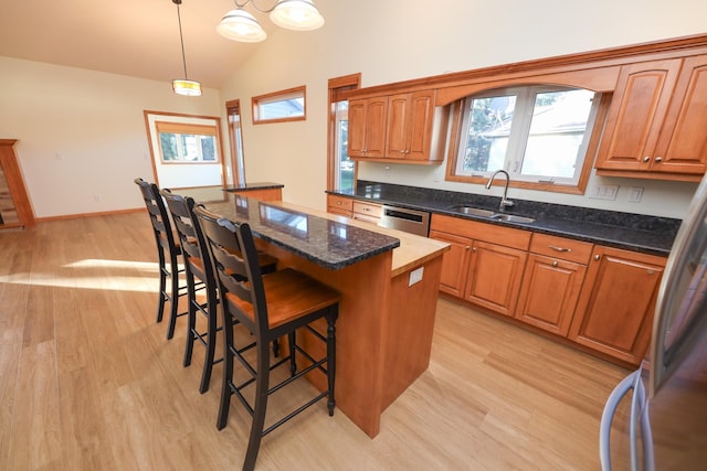 kitchen featuring sink, stainless steel appliances, light hardwood / wood-style flooring, a kitchen island, and pendant lighting