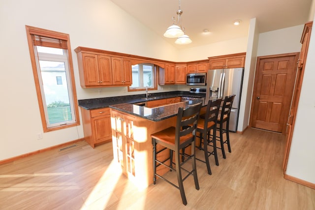 kitchen with stainless steel appliances, a kitchen island, sink, and light hardwood / wood-style flooring