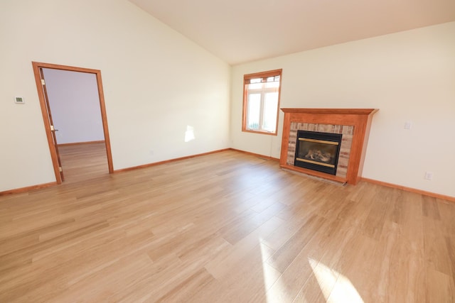 unfurnished living room with lofted ceiling, a tile fireplace, and light hardwood / wood-style floors