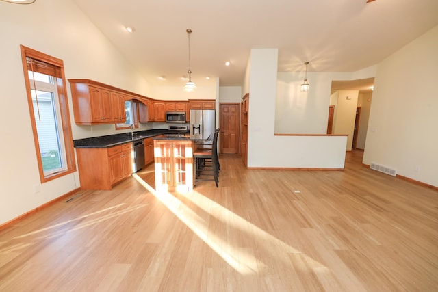 kitchen featuring a breakfast bar area, decorative light fixtures, light wood-type flooring, and appliances with stainless steel finishes