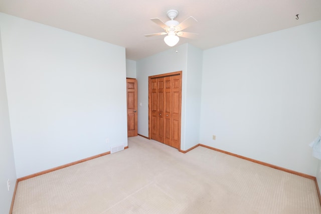 unfurnished bedroom featuring ceiling fan, light colored carpet, and a closet