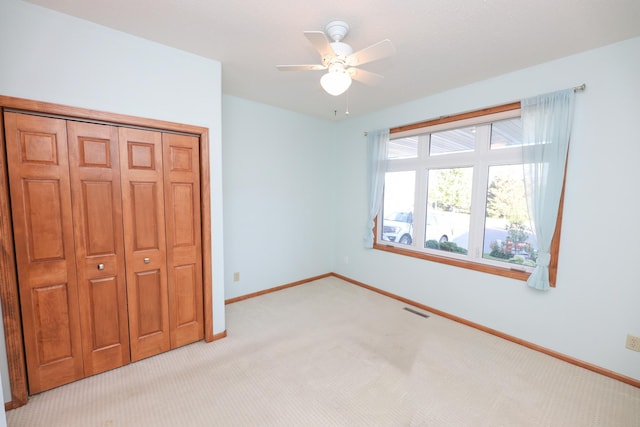 unfurnished bedroom featuring ceiling fan, a closet, and light carpet