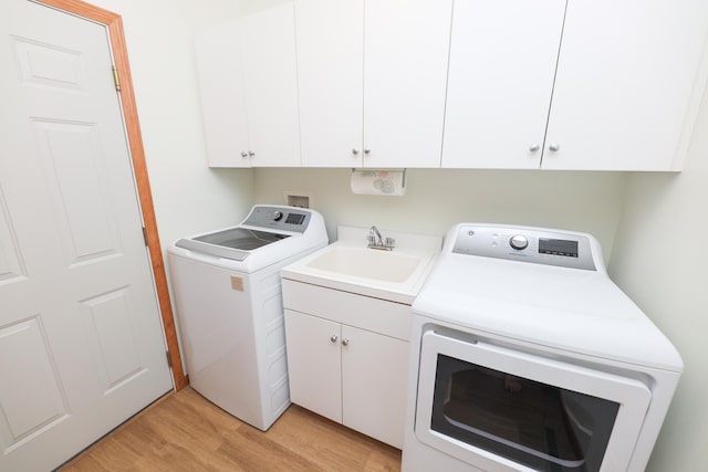 laundry room featuring washing machine and dryer, light wood-type flooring, cabinets, and sink