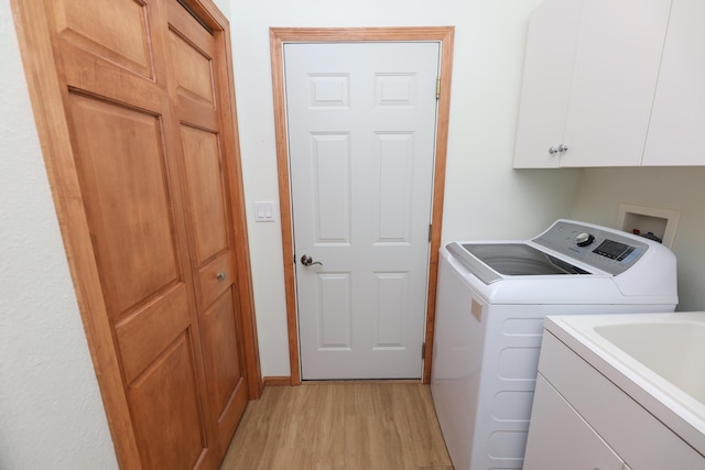 laundry room featuring cabinets, light hardwood / wood-style floors, and washer and clothes dryer