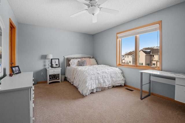 bedroom featuring light carpet, a textured ceiling, and ceiling fan