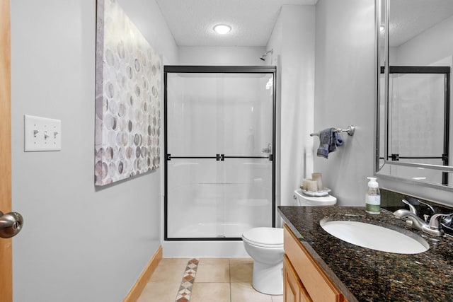 bathroom featuring a shower with shower door, tile patterned flooring, vanity, toilet, and a textured ceiling