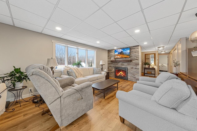 living room featuring a drop ceiling, a fireplace, and light hardwood / wood-style floors