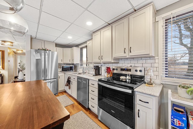 kitchen featuring stainless steel appliances, white cabinetry, sink, and a drop ceiling