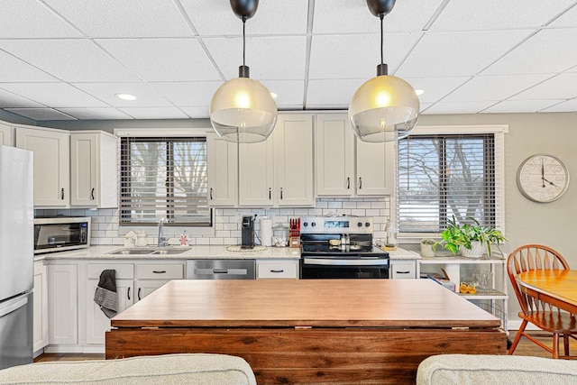 kitchen featuring sink, white cabinetry, a paneled ceiling, appliances with stainless steel finishes, and backsplash