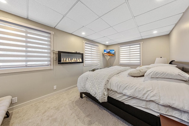 bedroom featuring light colored carpet and a drop ceiling