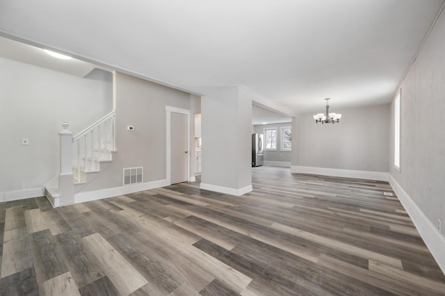 unfurnished living room featuring an inviting chandelier and dark hardwood / wood-style floors