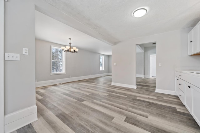 interior space with an inviting chandelier, light hardwood / wood-style floors, and a textured ceiling