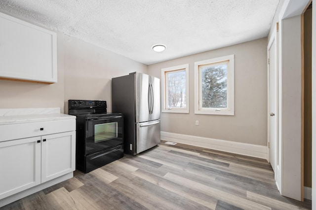 kitchen with stainless steel refrigerator, black range with electric stovetop, light hardwood / wood-style floors, a textured ceiling, and white cabinets