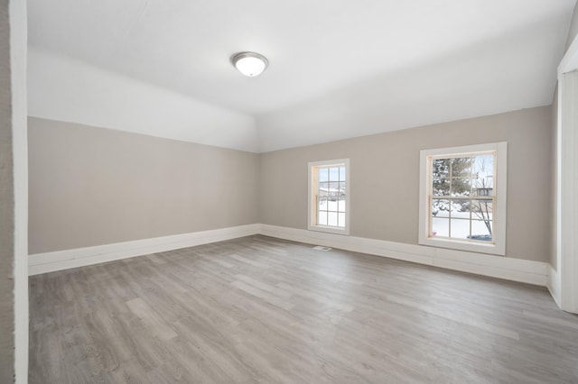 unfurnished room featuring lofted ceiling and light hardwood / wood-style floors