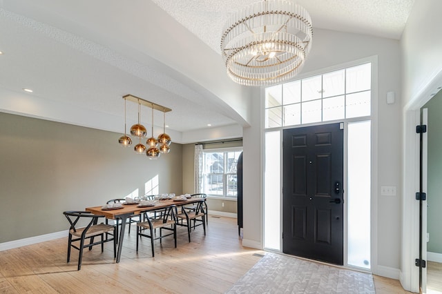 foyer featuring high vaulted ceiling, a textured ceiling, a notable chandelier, and light wood-type flooring