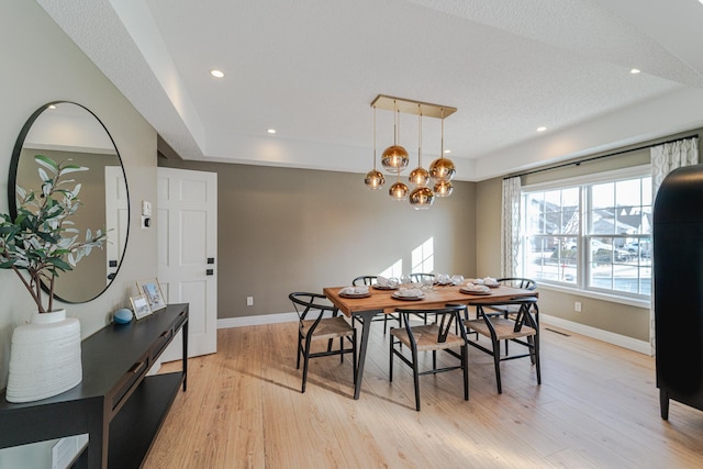 dining room featuring light hardwood / wood-style floors, a textured ceiling, and a notable chandelier