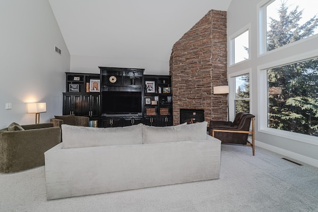 carpeted living room with a stone fireplace and high vaulted ceiling