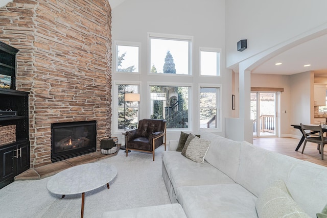 living room with a stone fireplace and high vaulted ceiling