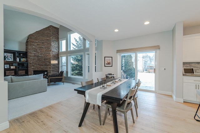 dining room with a stone fireplace and light hardwood / wood-style floors