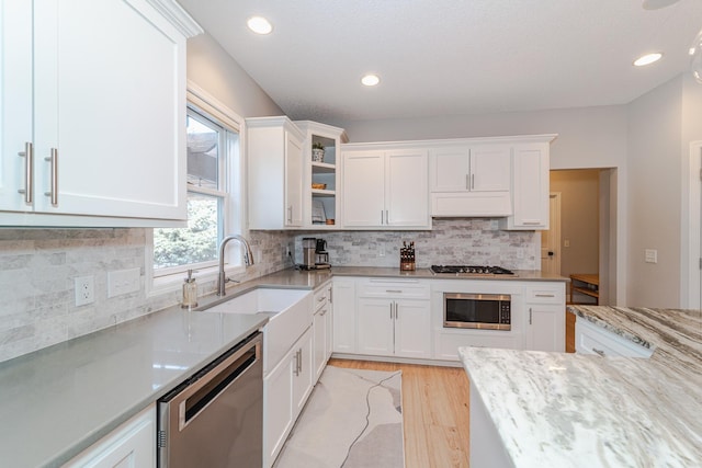 kitchen with light stone counters, stainless steel appliances, sink, and white cabinets