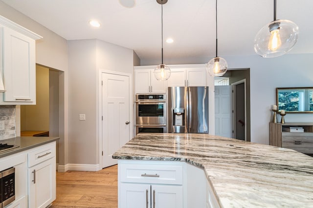 kitchen with stainless steel appliances, white cabinetry, hanging light fixtures, and backsplash