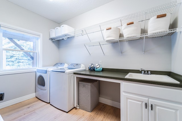 washroom with cabinets, sink, washing machine and clothes dryer, and light hardwood / wood-style floors