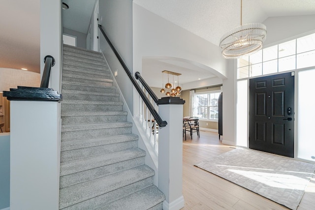 entrance foyer featuring high vaulted ceiling, a chandelier, light hardwood / wood-style floors, and a textured ceiling