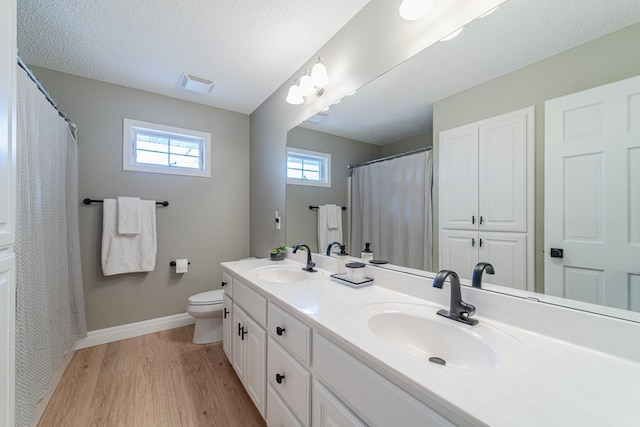 bathroom with vanity, hardwood / wood-style flooring, toilet, and a textured ceiling