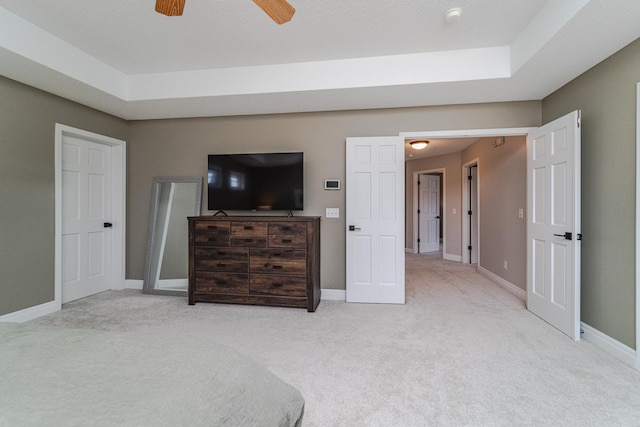 carpeted bedroom featuring ceiling fan and a raised ceiling