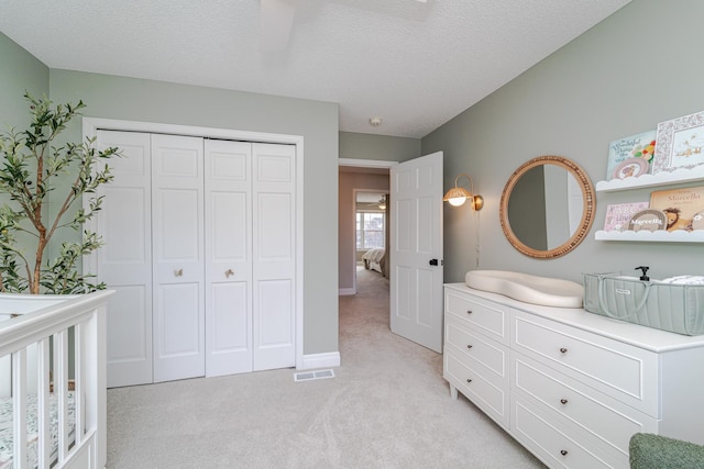 bedroom with light carpet, a closet, and a textured ceiling