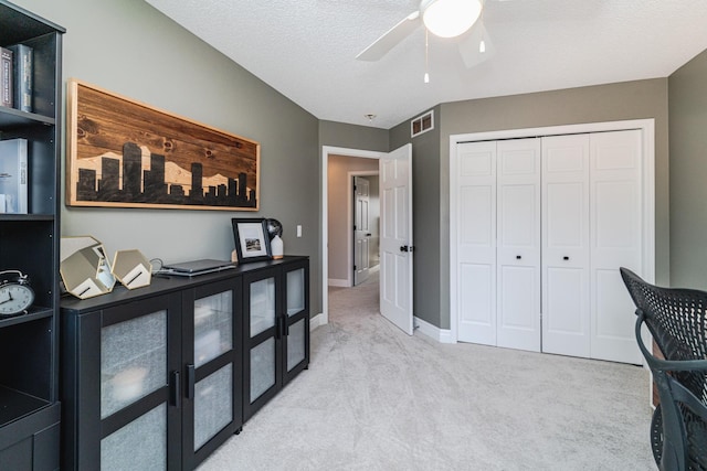 home office with ceiling fan, light carpet, and a textured ceiling