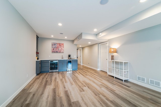 bar with wine cooler, sink, light hardwood / wood-style flooring, and blue cabinetry