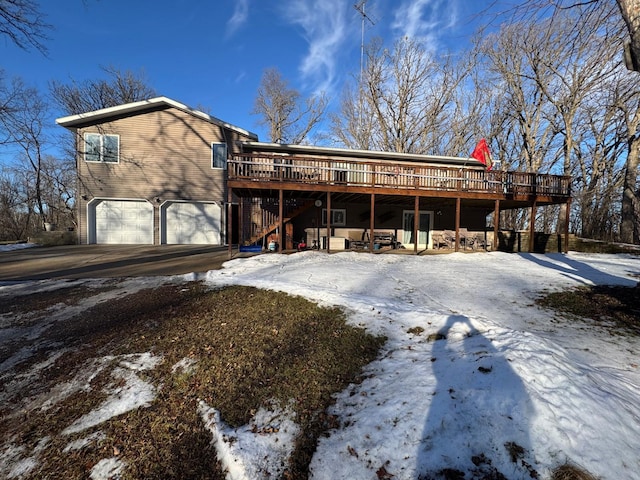 snow covered rear of property with a deck and a garage