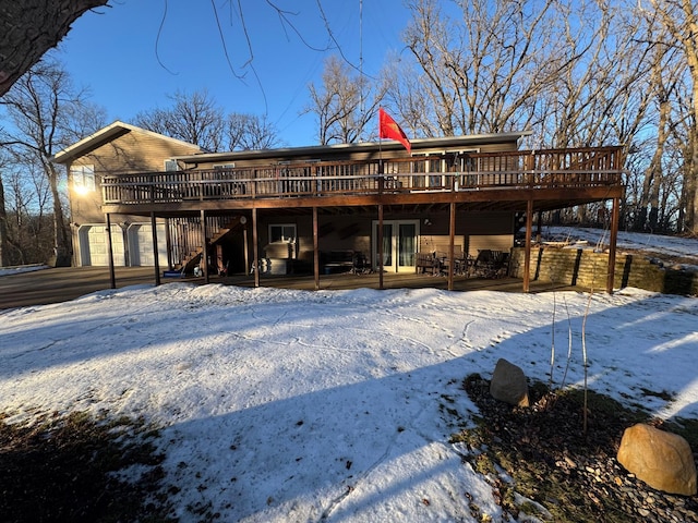 snow covered property featuring a wooden deck and a garage