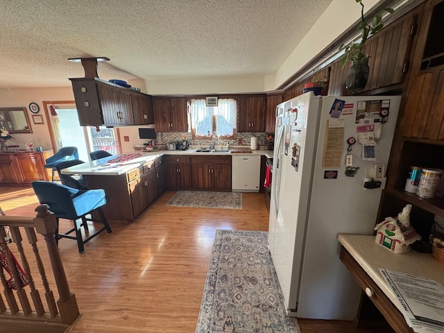 kitchen with light hardwood / wood-style floors, sink, white appliances, and dark brown cabinets