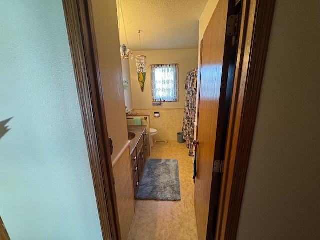 bathroom with toilet, vanity, a chandelier, and a textured ceiling